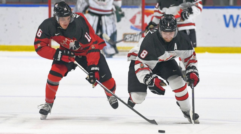 Kanādieši Semjuels Asinevaī (Nr. 16) un Breks Makkinlijs (Nr. 8) cīņā par ripu. Foto: Robert Lefebvre/Hockey Canada Images